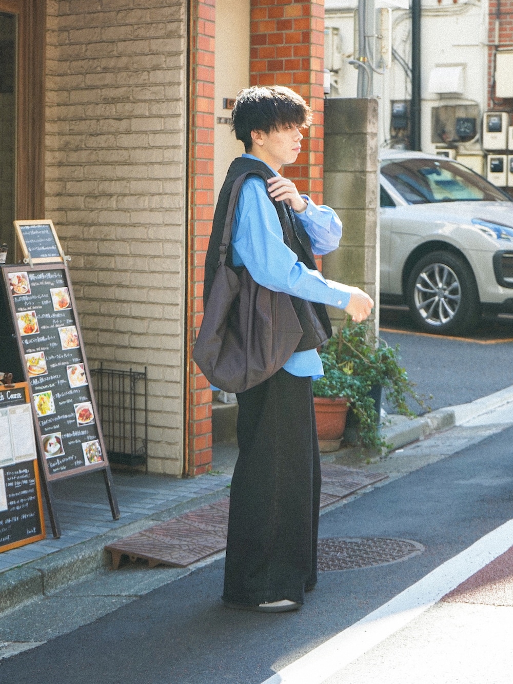 ブラック系のベスト、ブルー系のシャツ/ブラウス、ブラック系のデニムパンツを着用したメンズの春コーディネートの2枚目の写真