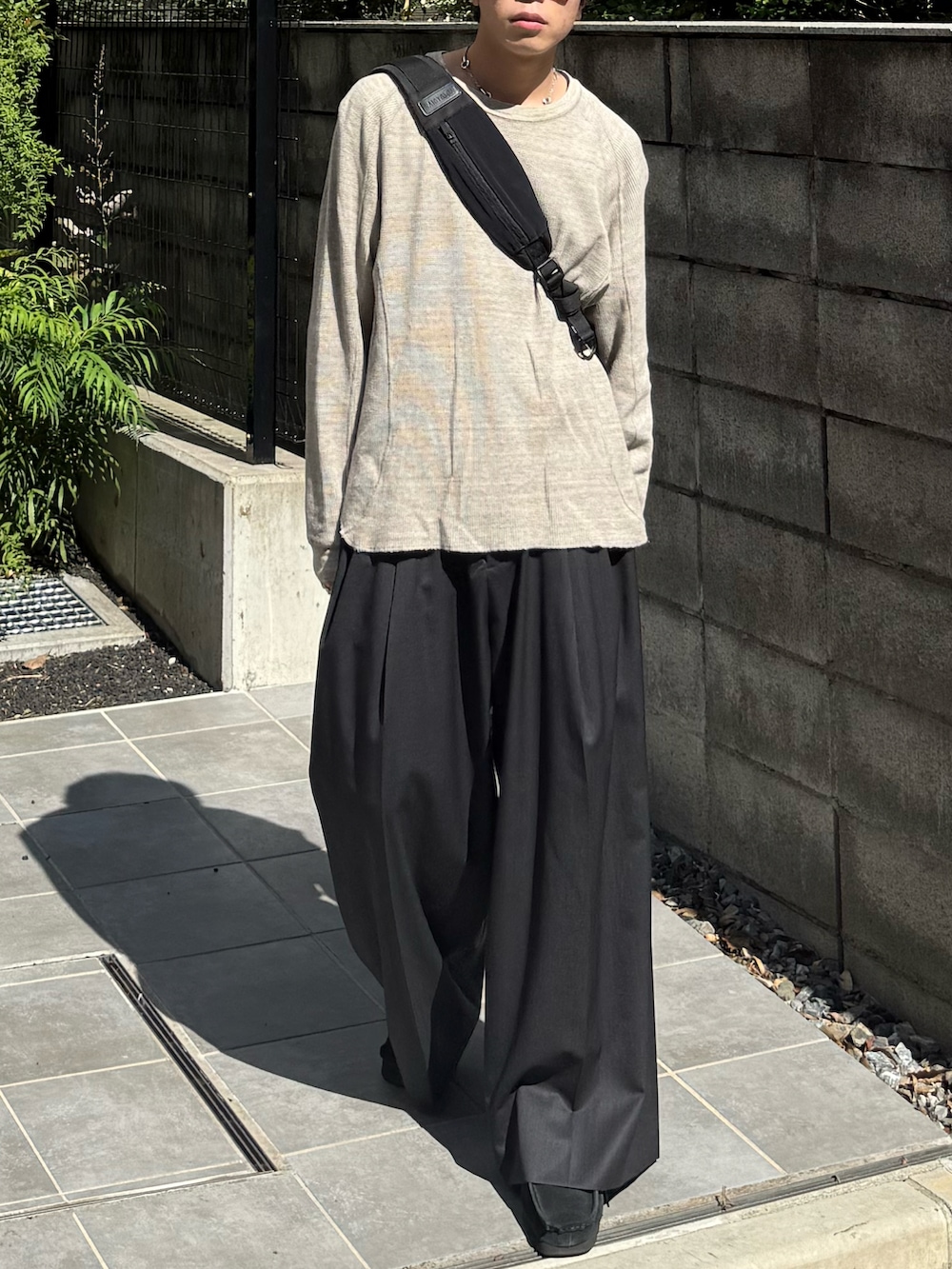 グレー系のTシャツ/カットソー、ブラック系のショルダーバッグ、グレー系のスラックスを着用したメンズの秋コーディネートの3枚目の写真