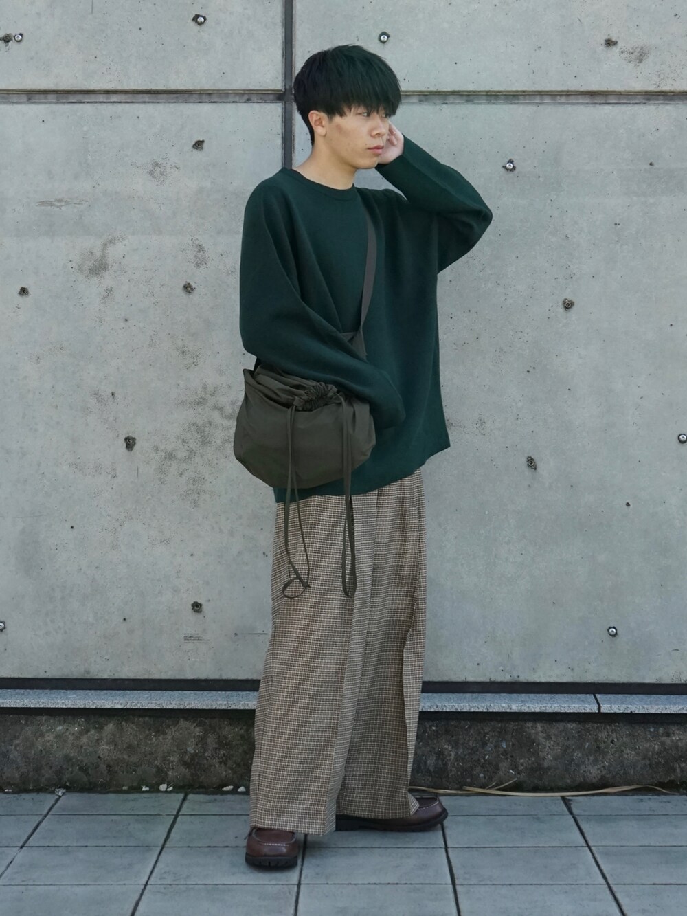 グリーン系のニット/セーター、ベージュ系のスラックス、ブラウン系のモカシン/デッキシューズを着用したメンズの秋コーディネートの3枚目の写真