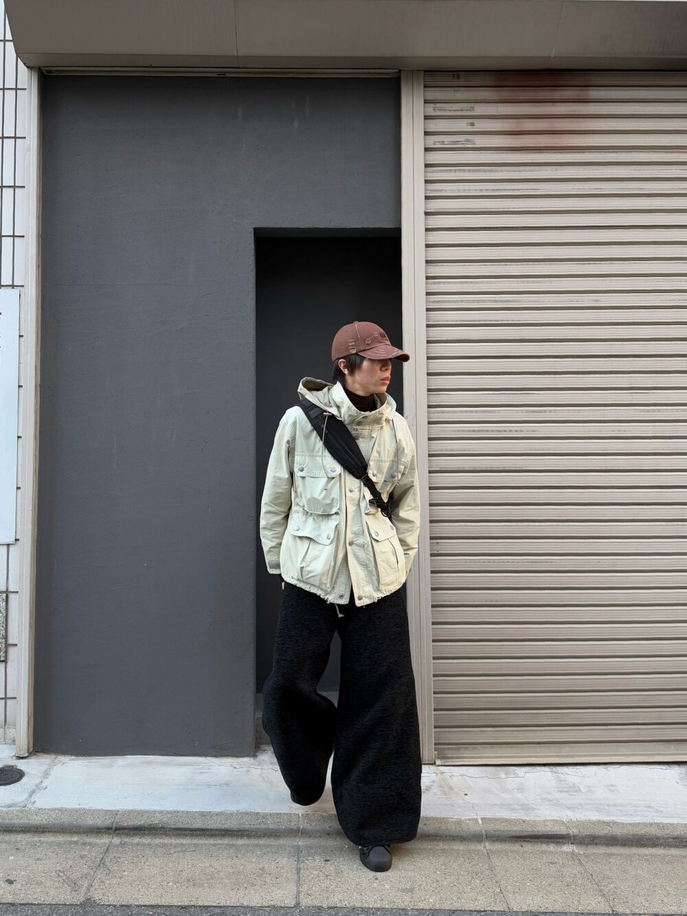 ブラック系のショルダーバッグ、ブラック系のスニーカー、ベージュ系のマウンテンパーカーを着用したメンズの冬コーディネートの3枚目の写真