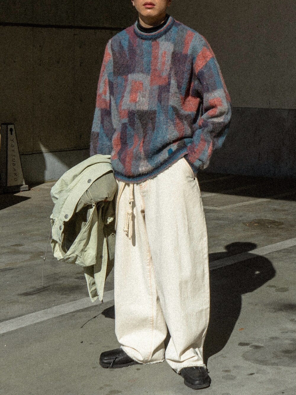 ブルー系のニット/セーター、ベージュ系のマウンテンパーカー、ブラック系のデニムパンツを着用したメンズの冬コーディネートの5枚目の写真