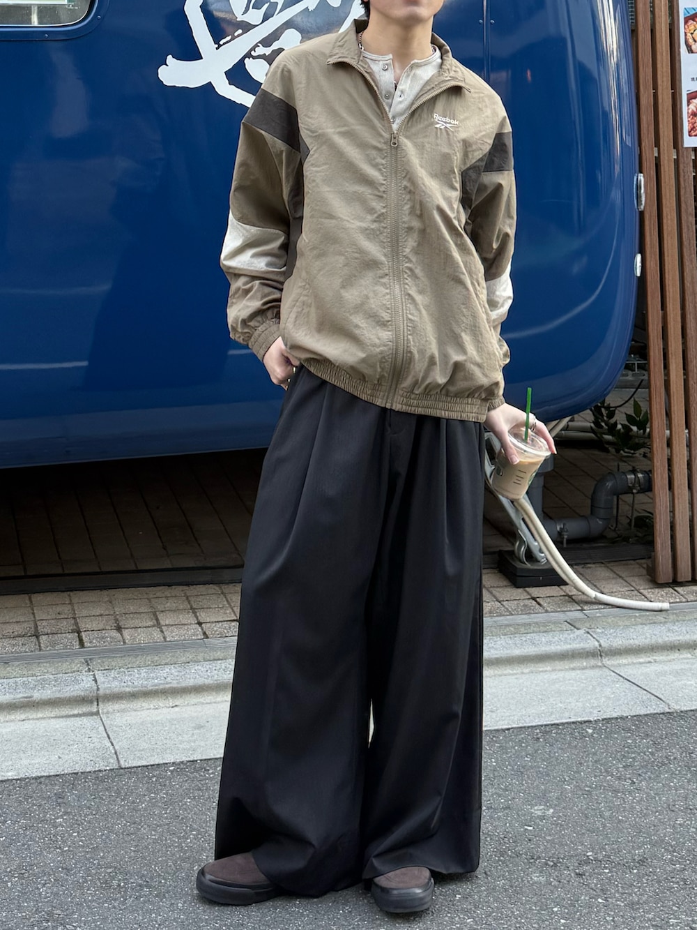 ベージュ系のナイロンジャケット、ベージュ系のTシャツ/カットソー、グレー系のスラックスを着用したメンズの春コーディネートの3枚目の写真