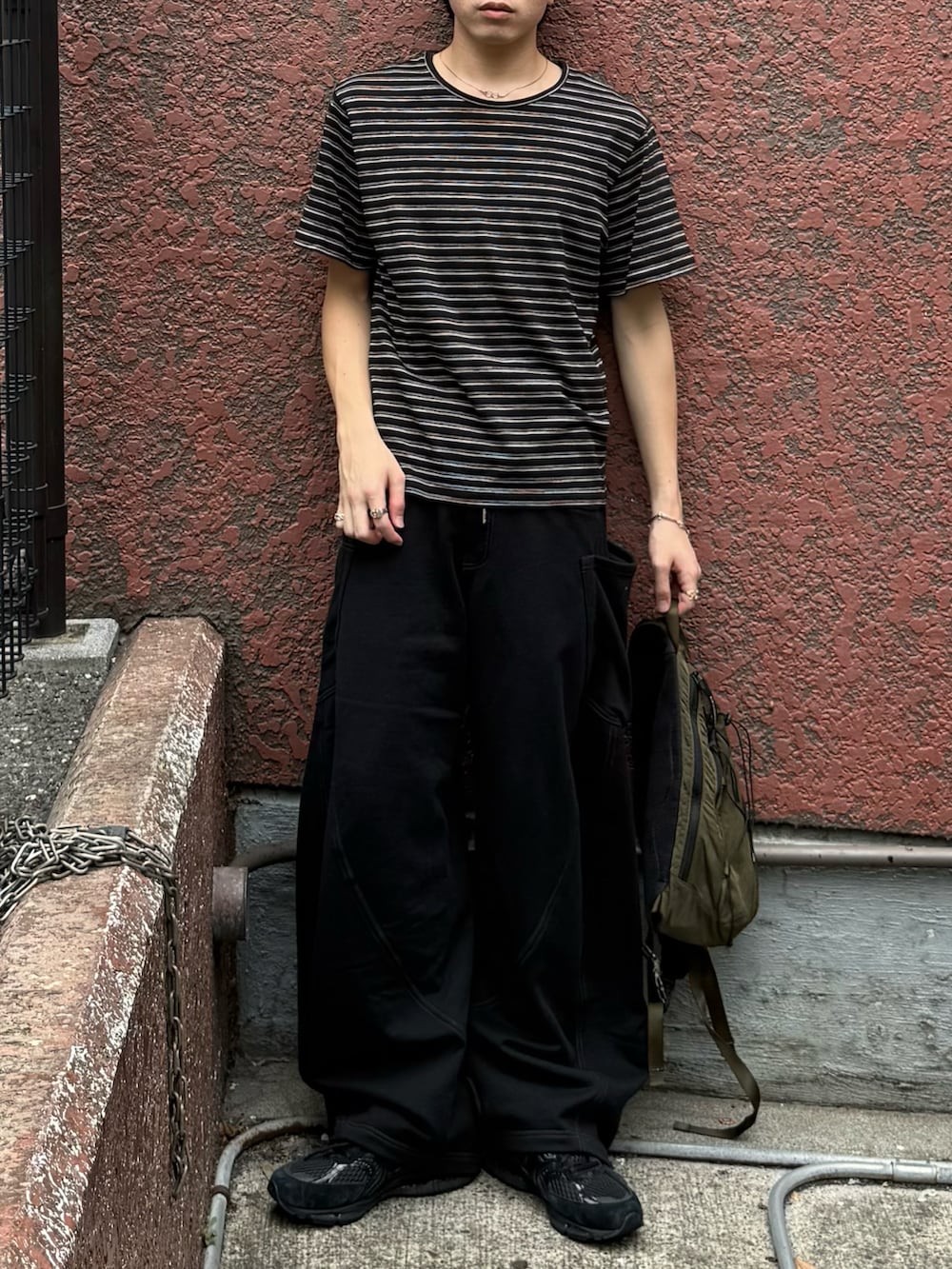 グリーン系のバックパック/リュック、ブラック系のTシャツ/カットソー、ブラック系のスウェットパンツを着用したメンズの秋コーディネートの5枚目の写真