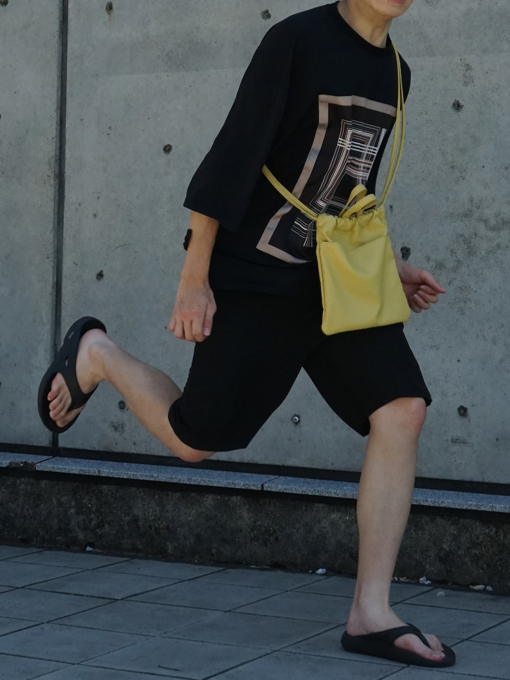 ブラック系のTシャツ/カットソー、ブラック系のスラックス、イエロー系のショルダーバッグを着用したメンズの夏コーディネートの5枚目の写真