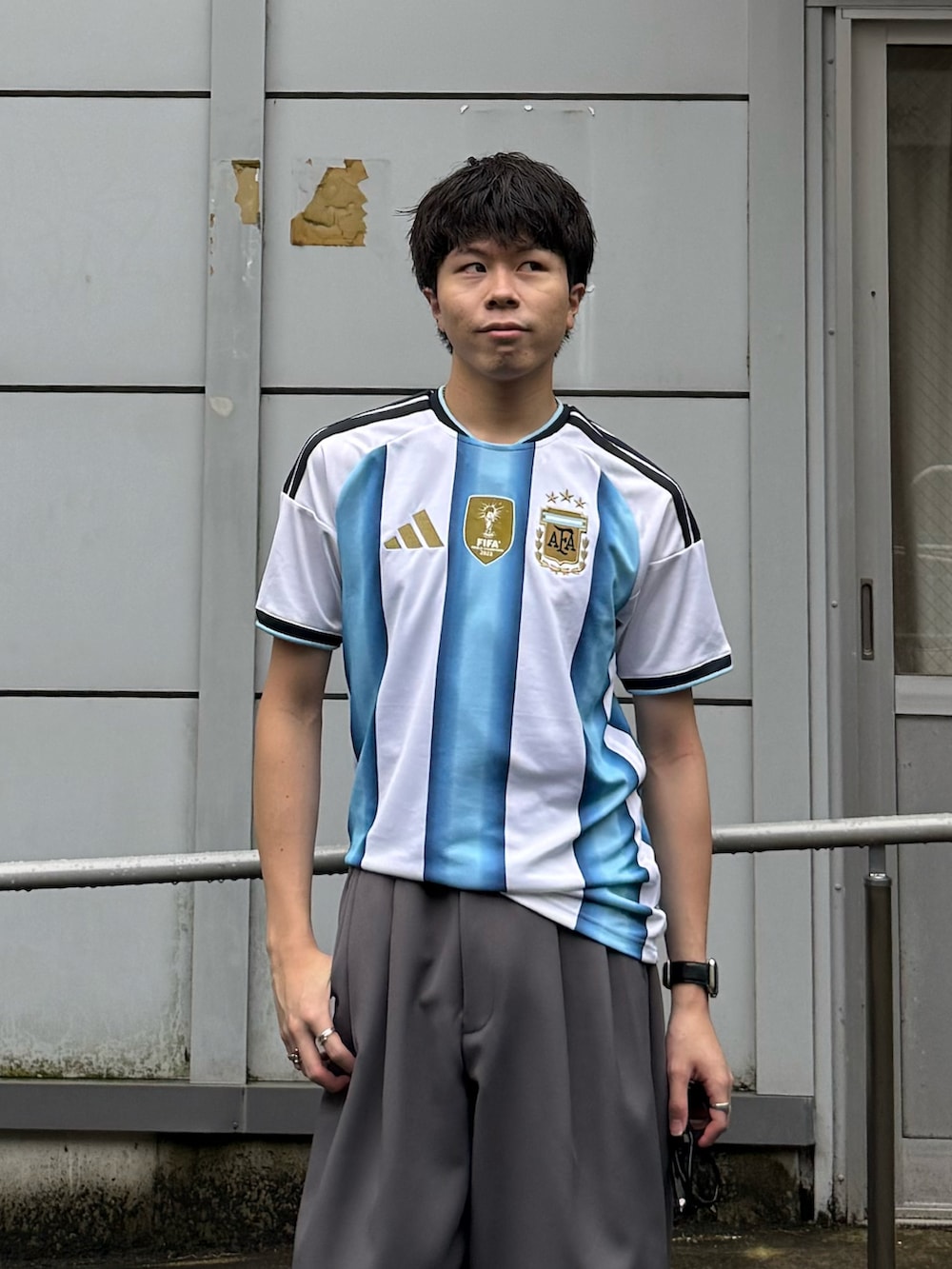 ホワイト系のTシャツ/カットソー、グレー系のパンツ、ブラック系のスニーカーを着用したメンズの夏コーディネートの3枚目の写真