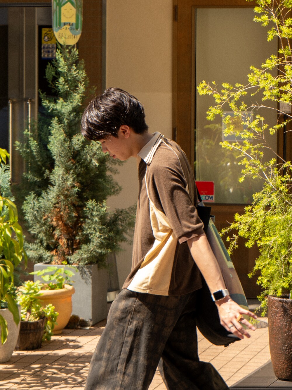 ブラウン系のポロシャツ、グリーン系のその他パンツ、ブラック系のトートバッグを着用したメンズの夏コーディネートの4枚目の写真