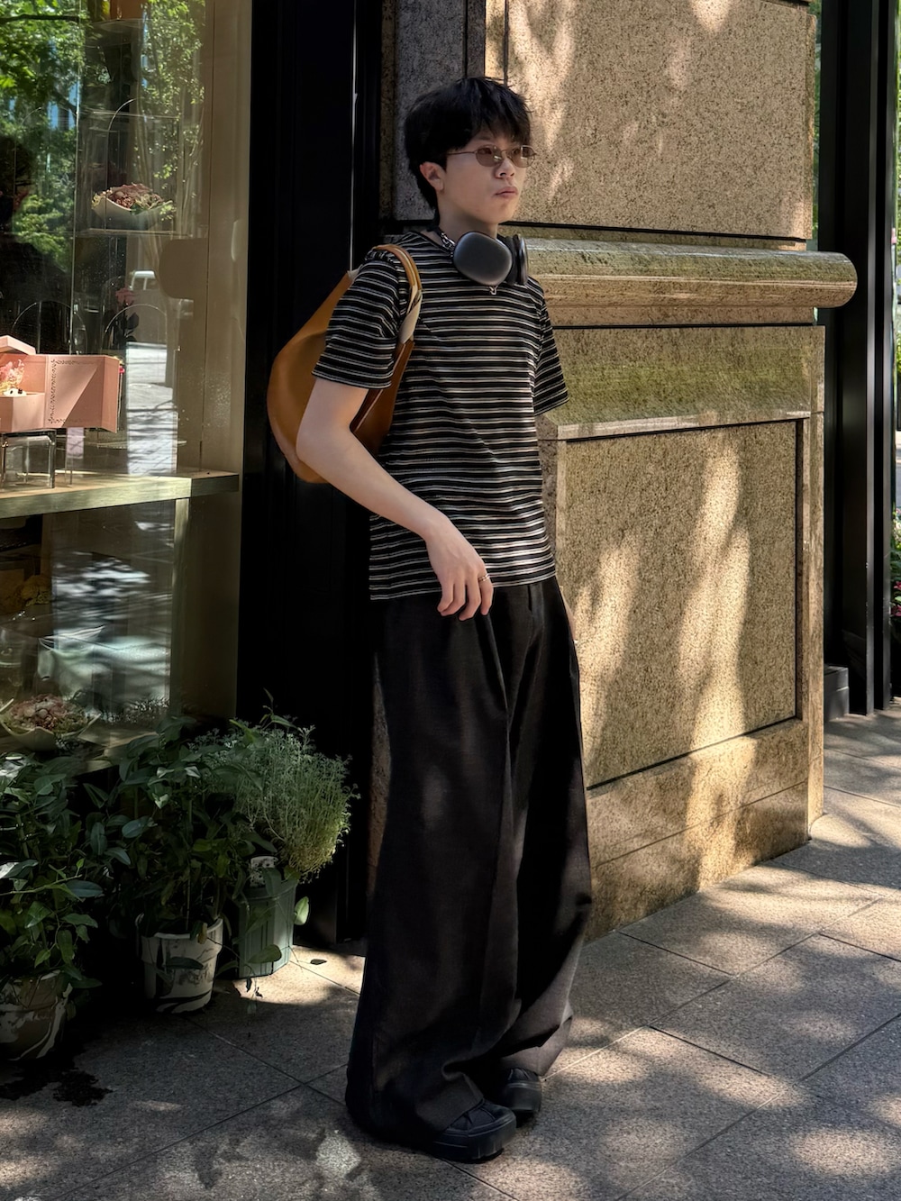 ブラック系のTシャツ/カットソー、ブラック系のスニーカー、ブラウン系のスラックスを着用したメンズの夏コーディネートの2枚目の写真