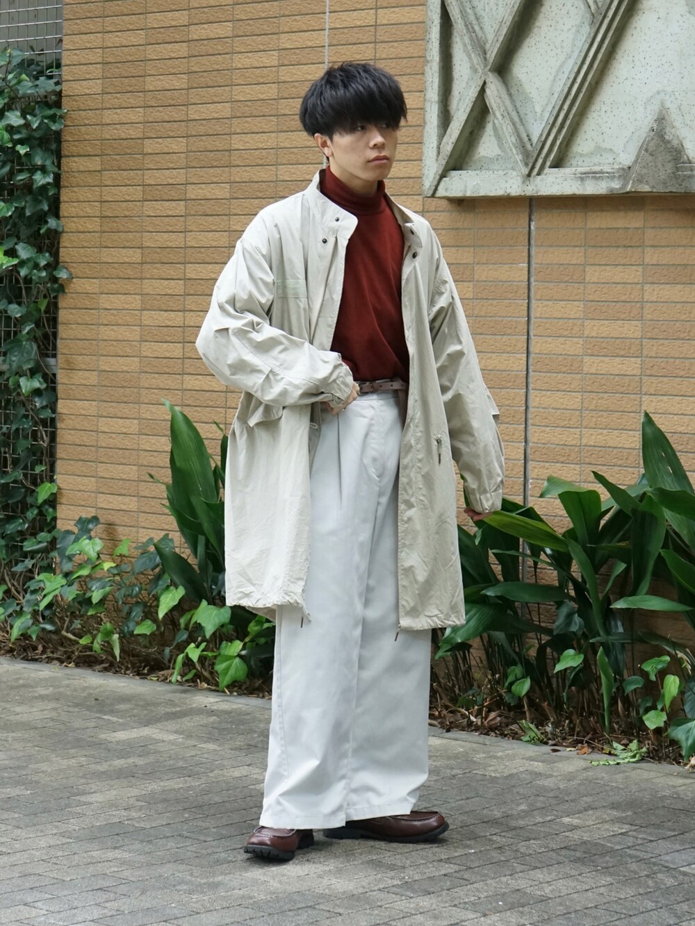 ベージュ系のモッズコート、レッド系のTシャツ/カットソー、ホワイト系のチノパンツを着用したメンズの秋コーディネートの4枚目の写真