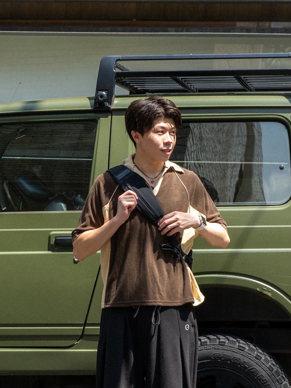 ブラウン系のポロシャツ、ブラック系のスウェットパンツ、ブラック系のショルダーバッグを着用したメンズの夏コーディネートの4枚目の写真