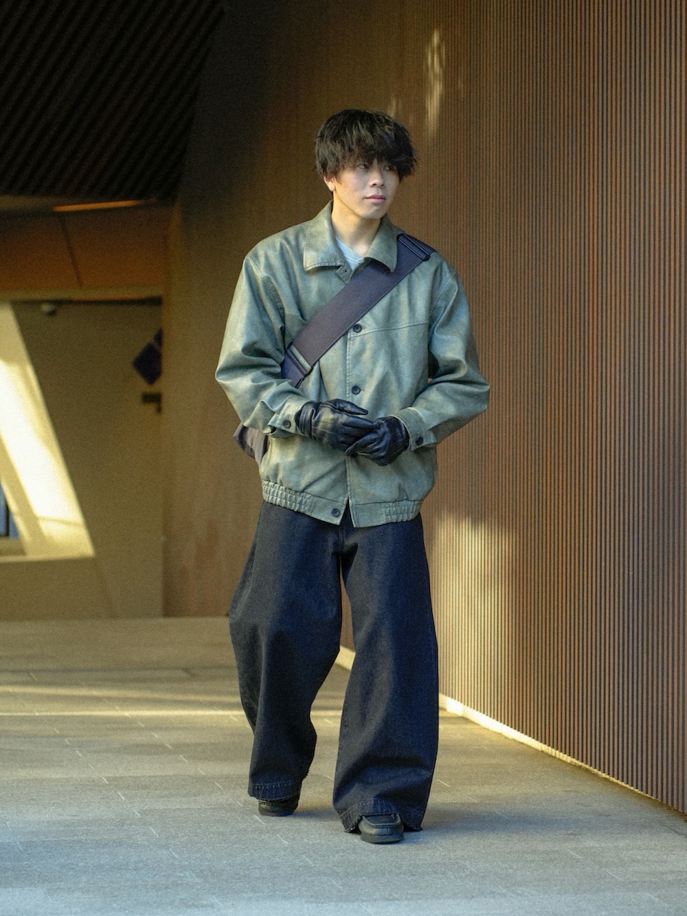 グレー系のブルゾン、ブラック系のデニムパンツ、グレー系のショルダーバッグを着用したメンズの冬コーディネートの2枚目の写真