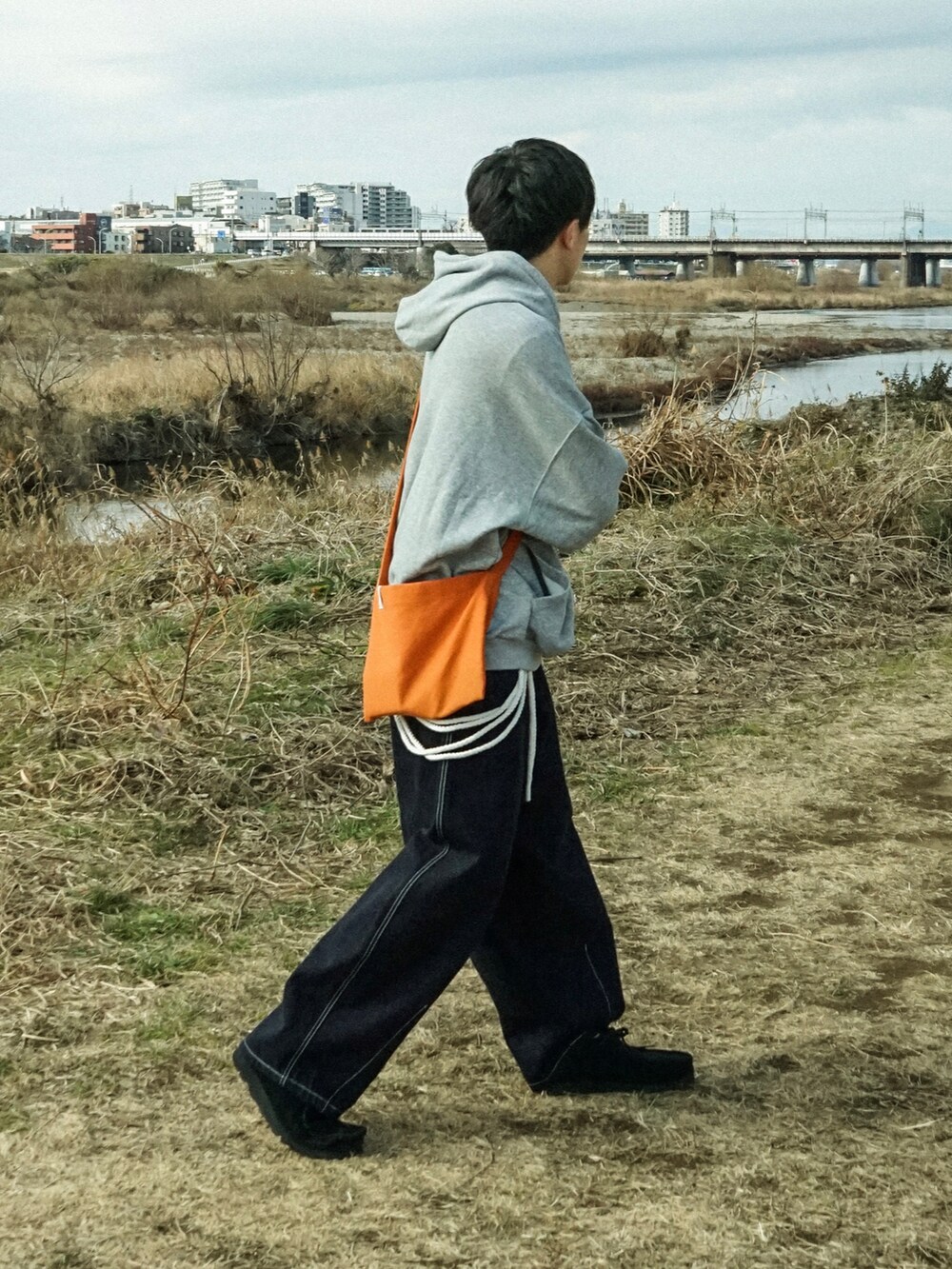 グレー系のパーカー、ブルー系のデニムパンツ、ブラック系のその他シューズを着用したメンズの冬コーディネートの2枚目の写真