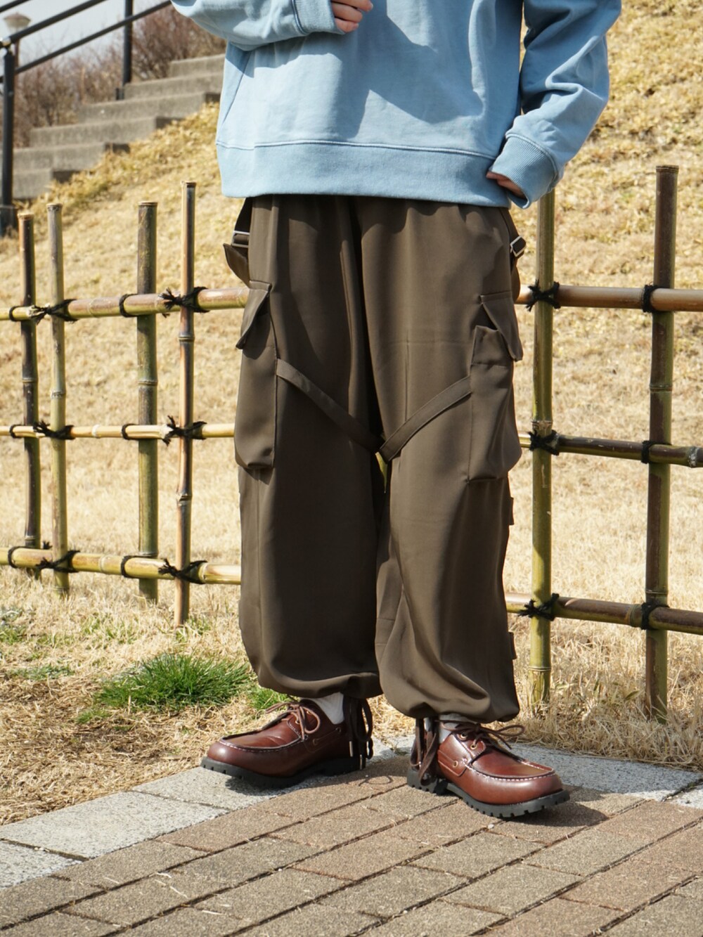 ブルー系のスウェット、グリーン系のサロペット/オーバーオール、ブラウン系のモカシン/デッキシューズを着用したメンズの冬コーディネートの4枚目の写真