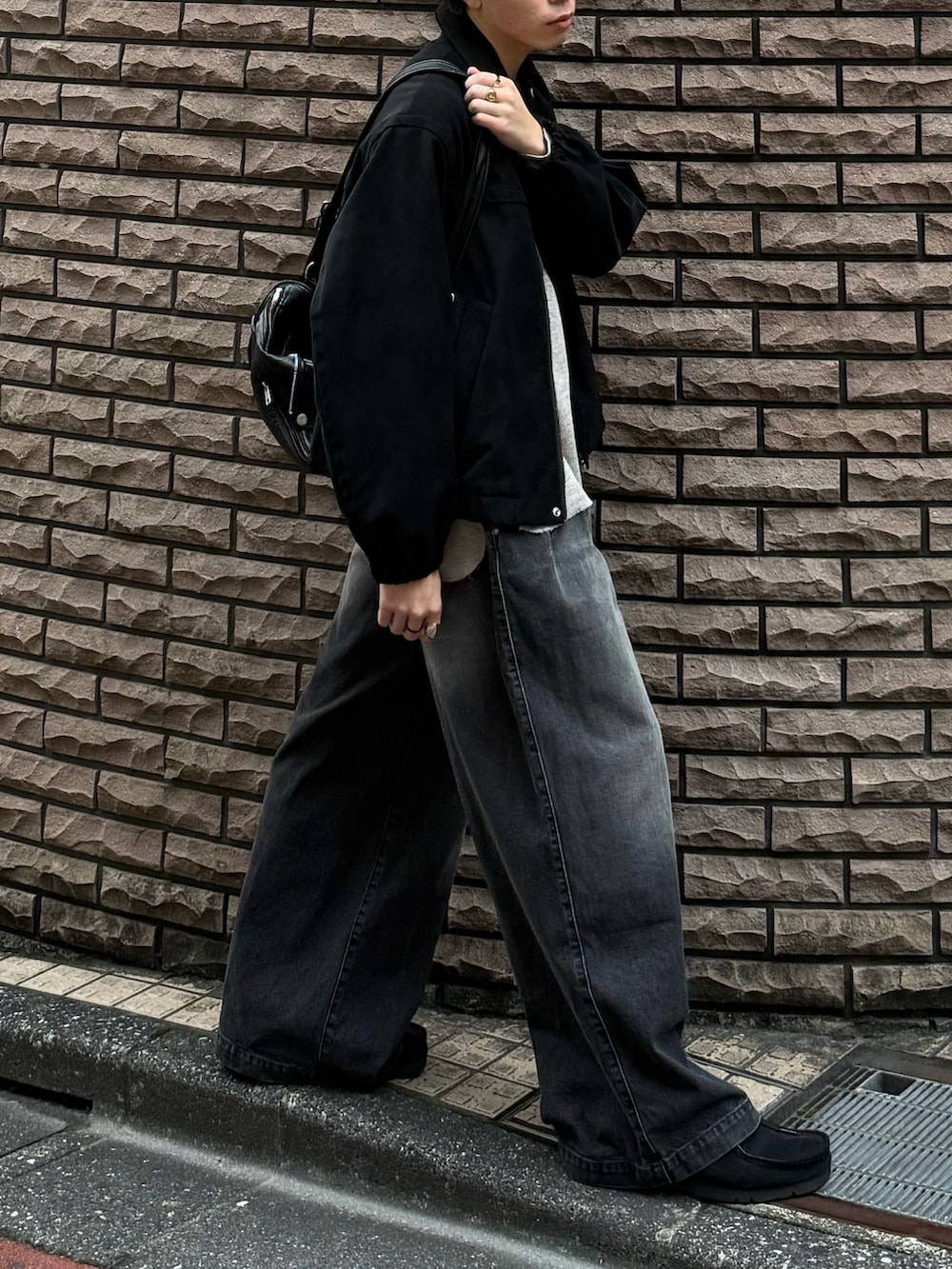 ブラック系のブルゾン、グレー系のTシャツ/カットソー、ブラック系のデニムパンツを着用したメンズの秋コーディネートの4枚目の写真