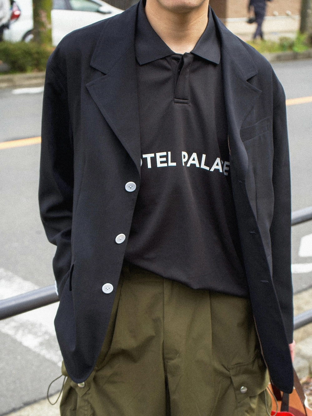 ブラック系のテーラードジャケット、ブラック系のポロシャツ、グリーン系のカーゴパンツを着用したメンズの春コーディネートの3枚目の写真