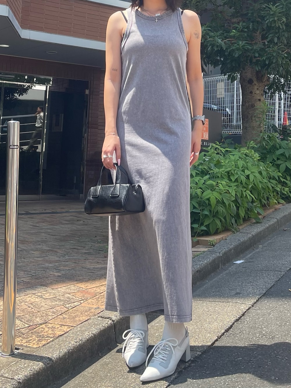 グレー系のワンピース、ブラック系のハンドバッグ、ホワイト系のパンプスを着用したレディースの夏コーディネートの3枚目の写真