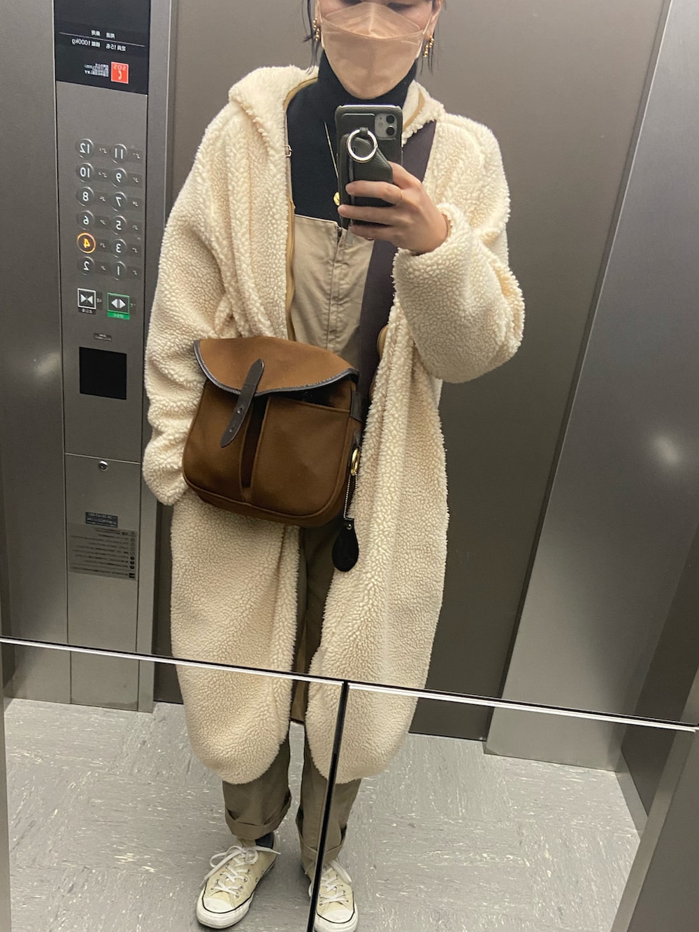 ホワイト系のスニーカー、ベージュ系のその他アウター、ブラウン系のサロペット/オーバーオールを着用したレディースの冬コーディネートの3枚目の写真