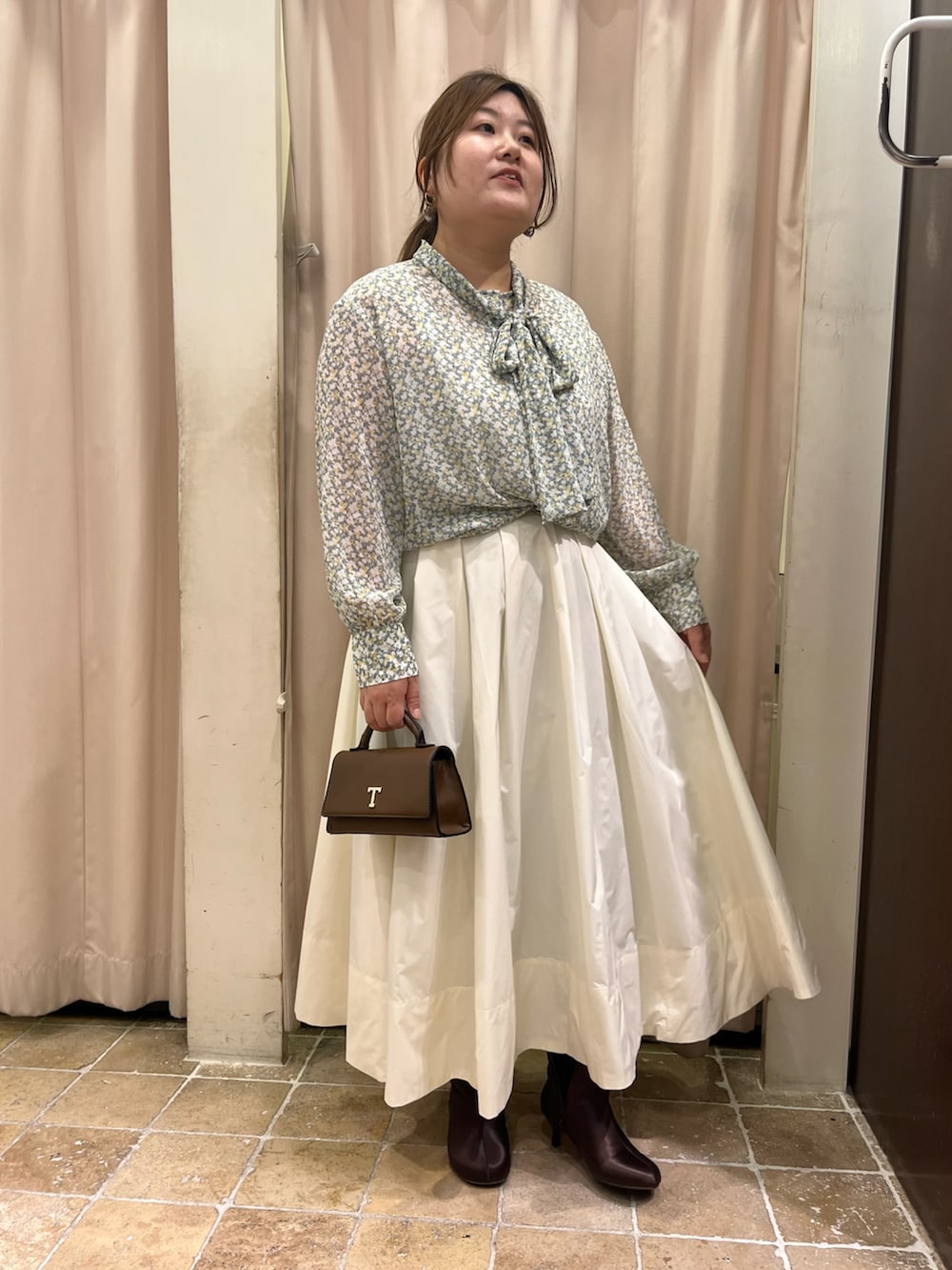 ベージュ系のスカート、ブラウン系のハンドバッグ、イエロー系のシャツ/ブラウスを着用したレディースの冬コーディネートの2枚目の写真