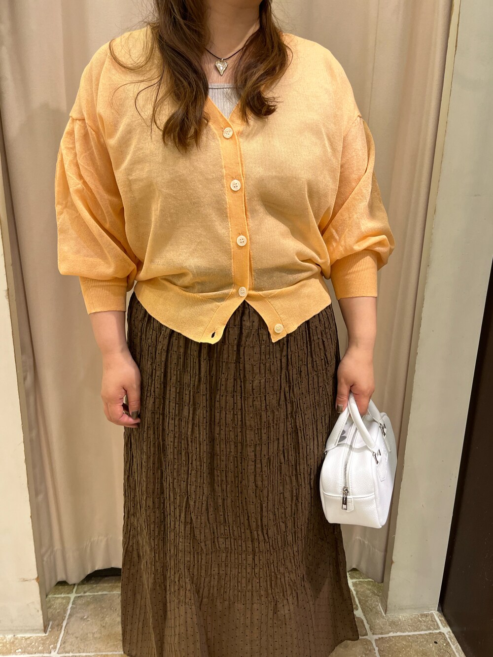 ベージュ系のタンクトップ、ホワイト系のハンドバッグ、ブラック系のサンダルを着用したレディースの春コーディネートの2枚目の写真