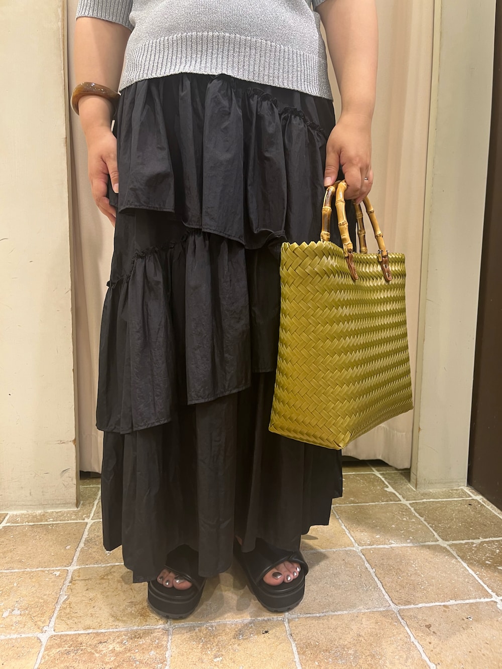 イエロー系のハンドバッグ、ブラック系のサンダル、ブラック系のスカートを着用したレディースの夏コーディネートの3枚目の写真