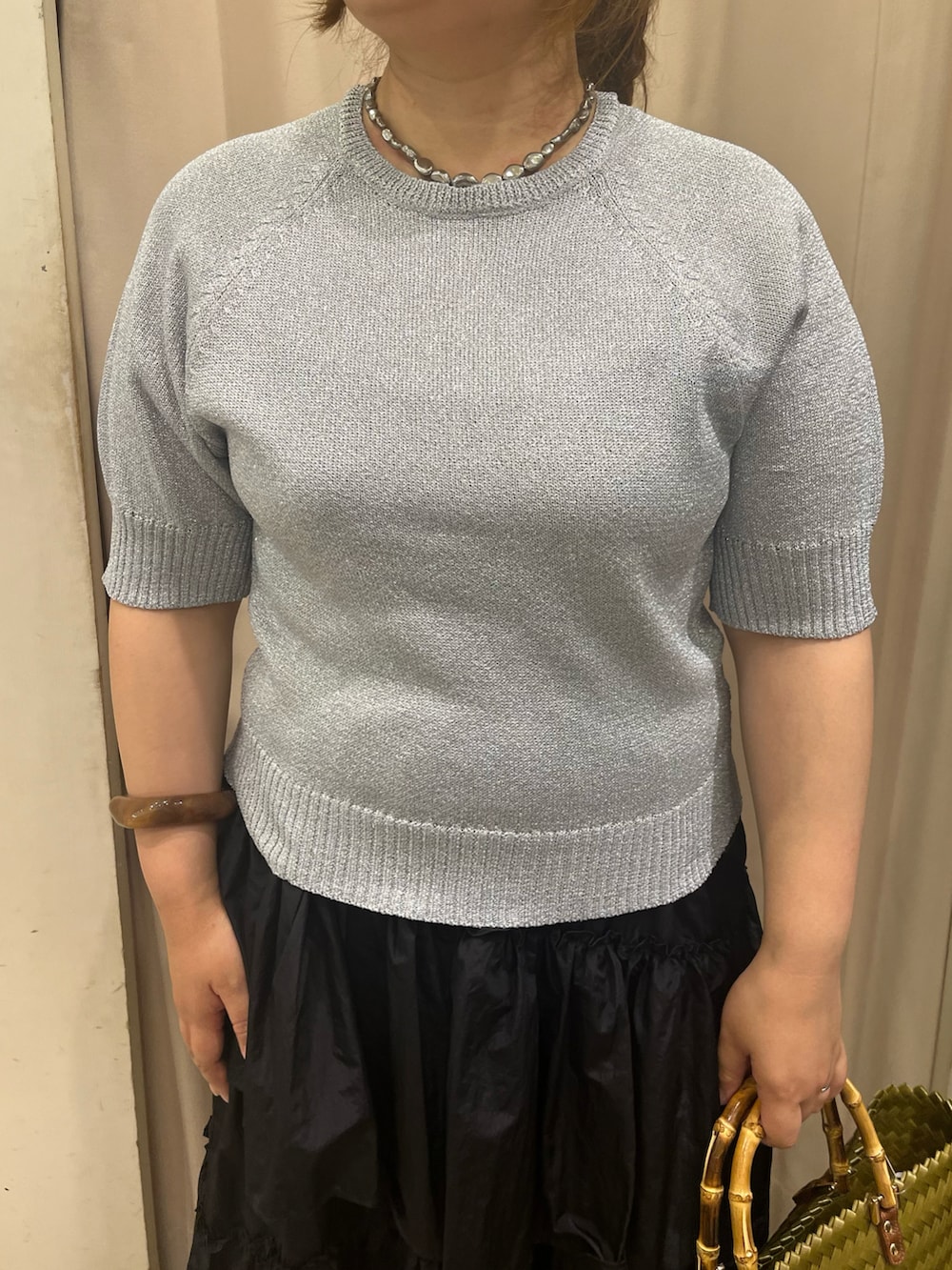 イエロー系のハンドバッグ、ブラック系のサンダル、ブラック系のスカートを着用したレディースの夏コーディネートの2枚目の写真