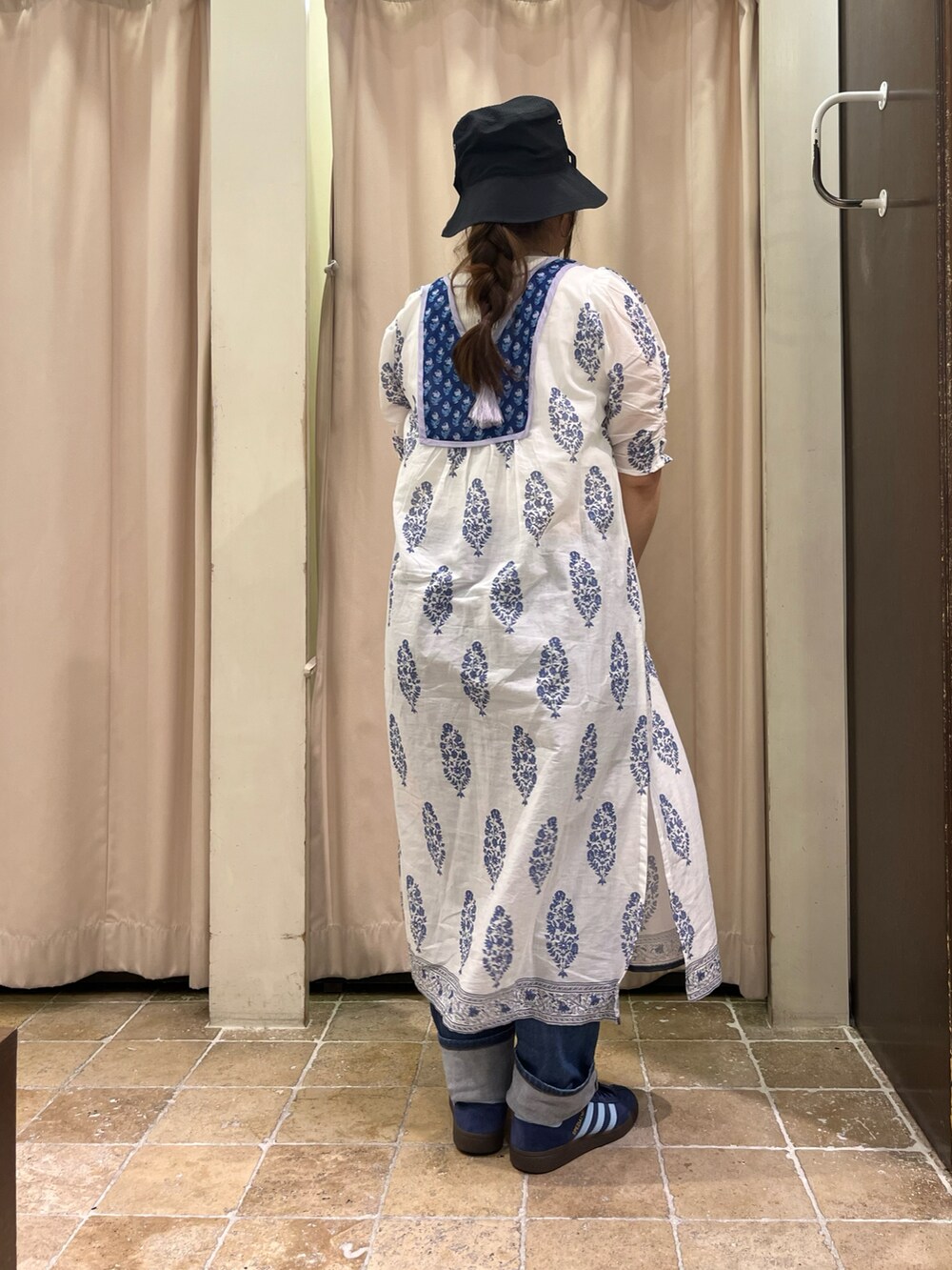 ブラック系のハンドバッグ、ホワイト系のワンピース、ブルー系のスニーカーを着用したレディースの春コーディネートの2枚目の写真