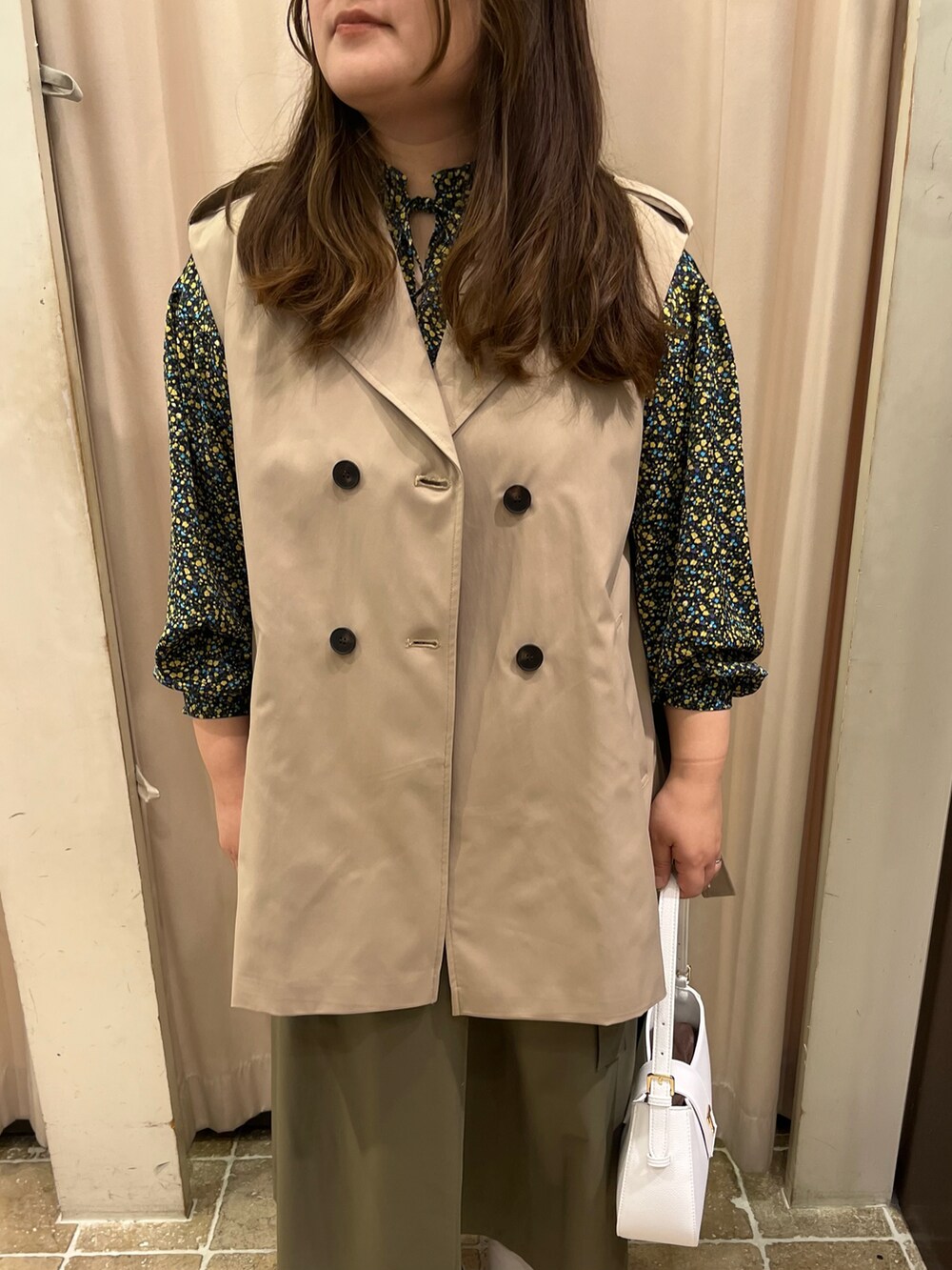 ベージュ系のベスト、イエロー系のシャツ/ブラウス、グリーン系のスカートを着用したレディースの冬コーディネートの3枚目の写真