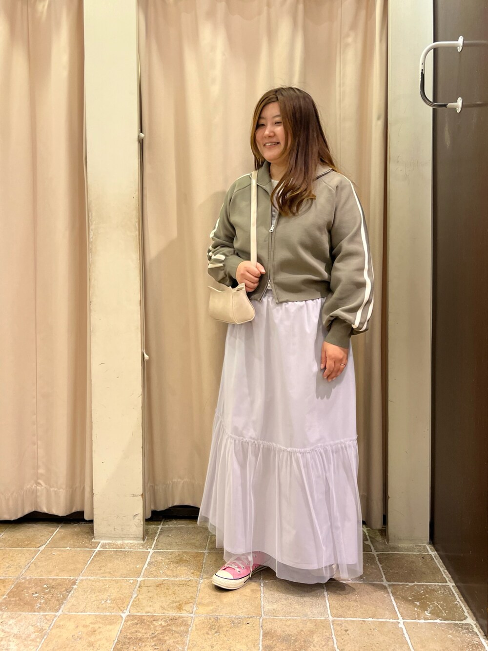 ピンク系のスニーカー、グレー系のスカート、ホワイト系のハンドバッグを着用したレディースの春コーディネートの2枚目の写真