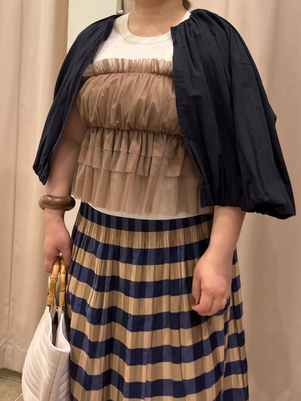 ブラウン系のシャツ/ブラウス、ブルー系のスカート、ブラック系のブルゾンを着用したレディースの春コーディネートの2枚目の写真