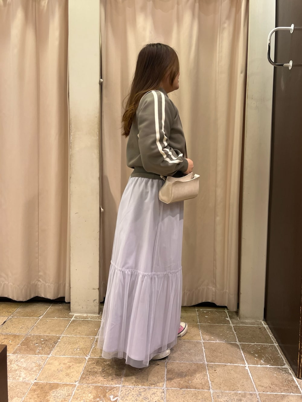 ピンク系のスニーカー、グレー系のスカート、ホワイト系のハンドバッグを着用したレディースの春コーディネートの3枚目の写真