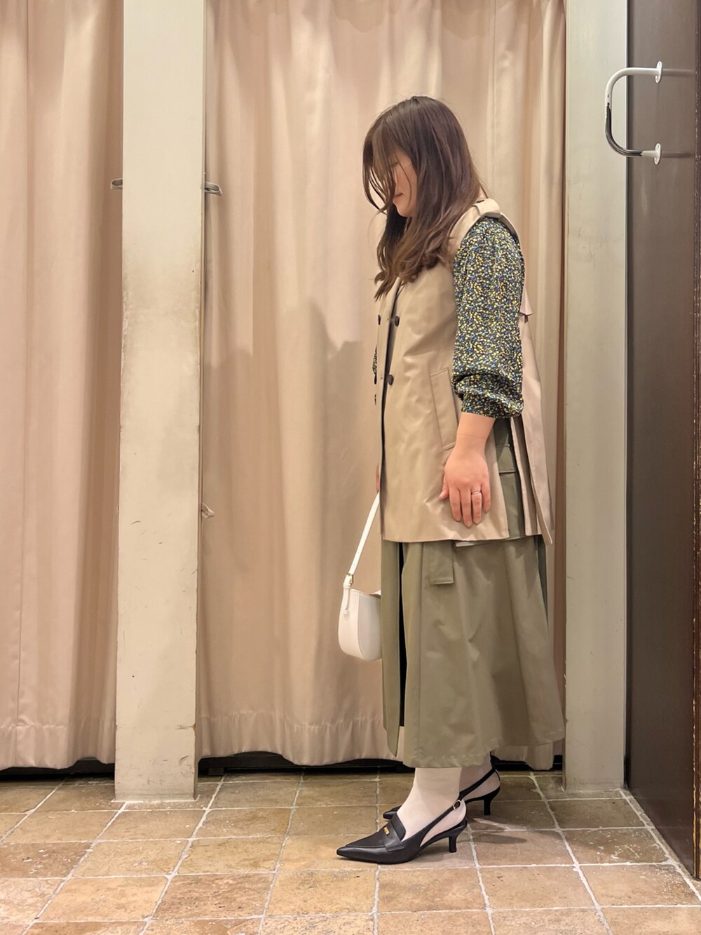 ベージュ系のベスト、イエロー系のシャツ/ブラウス、グリーン系のスカートを着用したレディースの冬コーディネートの2枚目の写真