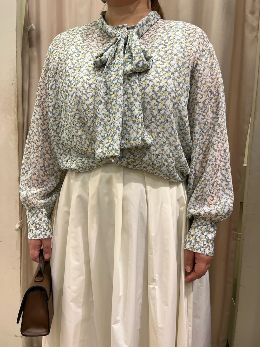 ベージュ系のスカート、ブラウン系のハンドバッグ、イエロー系のシャツ/ブラウスを着用したレディースの冬コーディネートの3枚目の写真