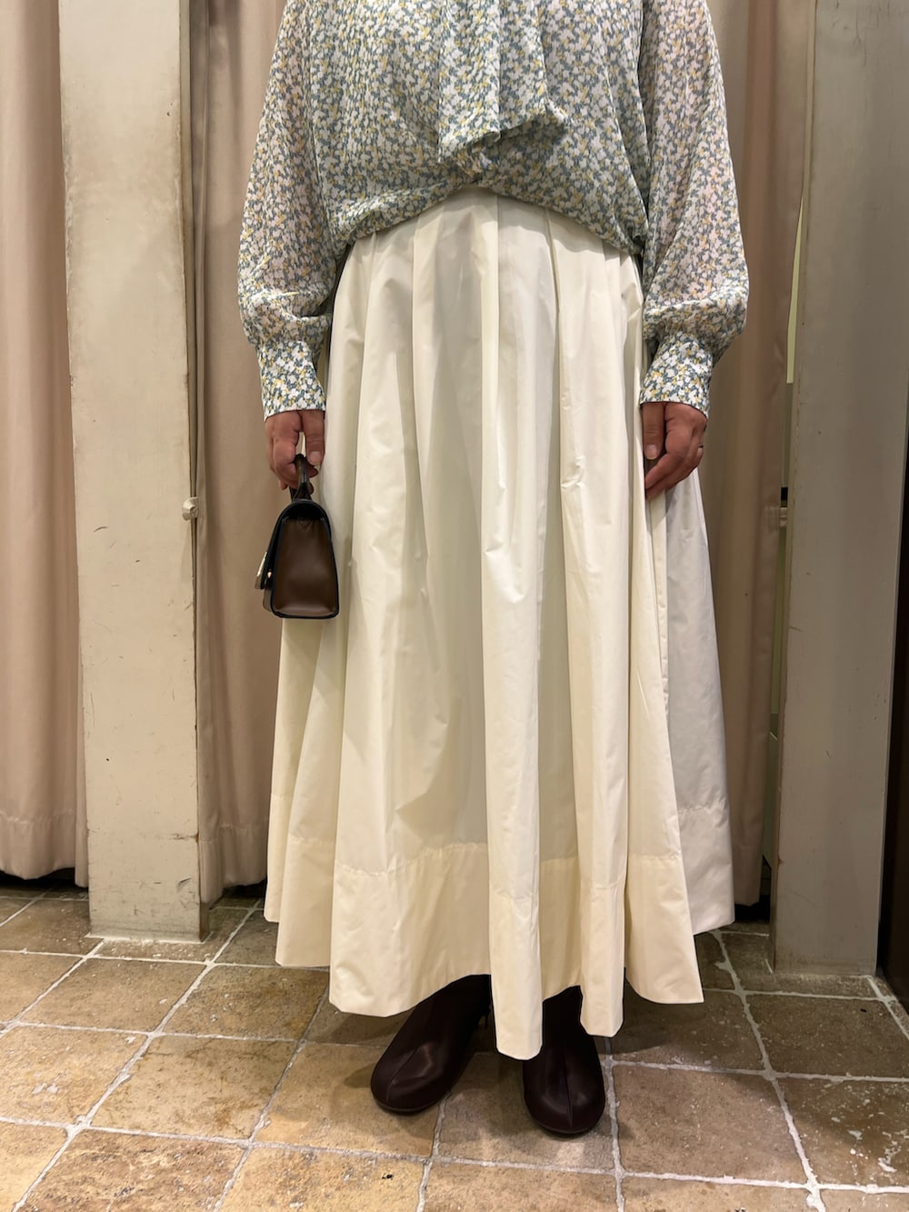 ベージュ系のスカート、ブラウン系のハンドバッグ、イエロー系のシャツ/ブラウスを着用したレディースの冬コーディネートの4枚目の写真