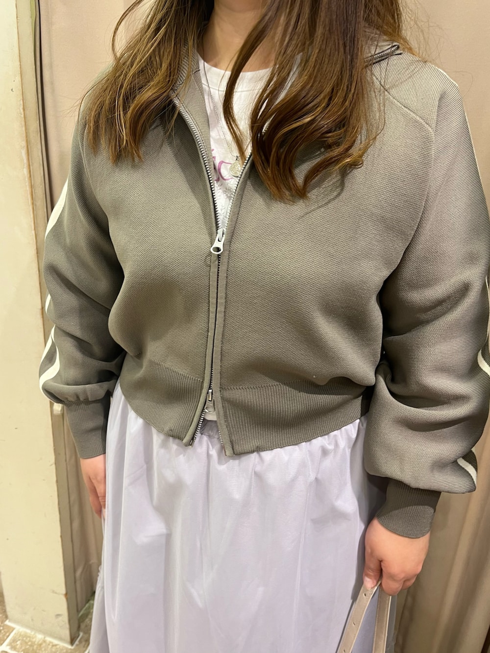 ピンク系のスニーカー、グレー系のスカート、ホワイト系のハンドバッグを着用したレディースの春コーディネートの4枚目の写真