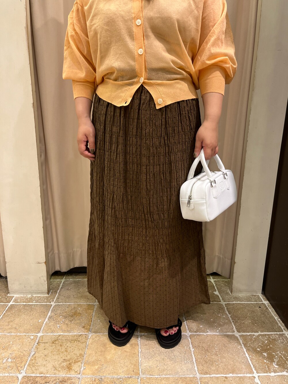 ベージュ系のタンクトップ、ホワイト系のハンドバッグ、ブラック系のサンダルを着用したレディースの春コーディネートの3枚目の写真