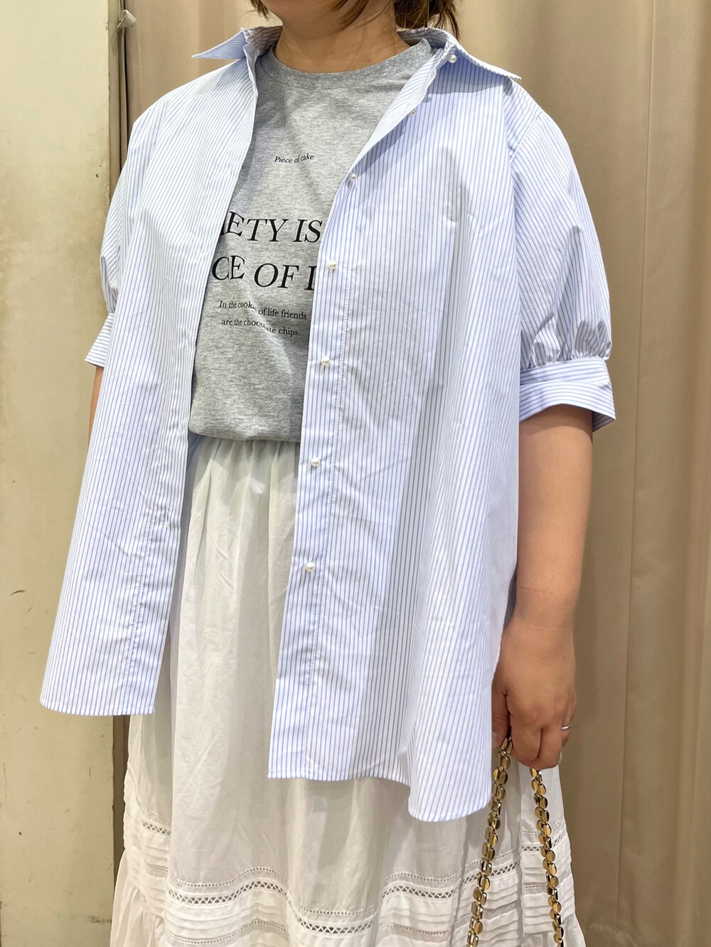 ブルー系のシャツ/ブラウス、ホワイト系のスカート、ブラック系のサンダルを着用したレディースの春コーディネートの2枚目の写真