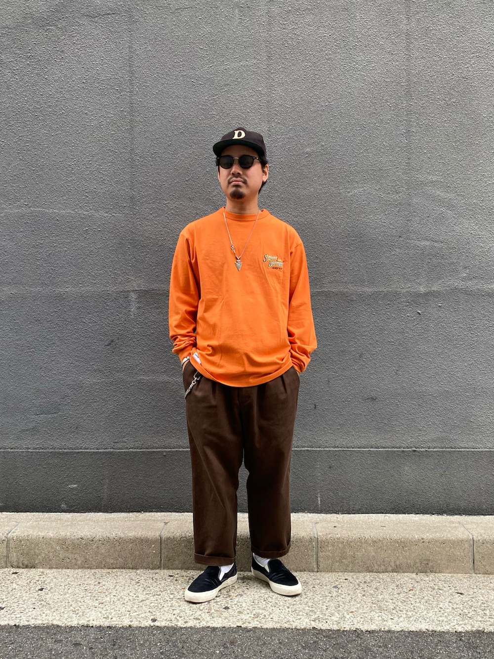 オレンジ系のTシャツ/カットソー、ブラウン系のチノパンツを着用したメンズの冬コーディネートの2枚目の写真