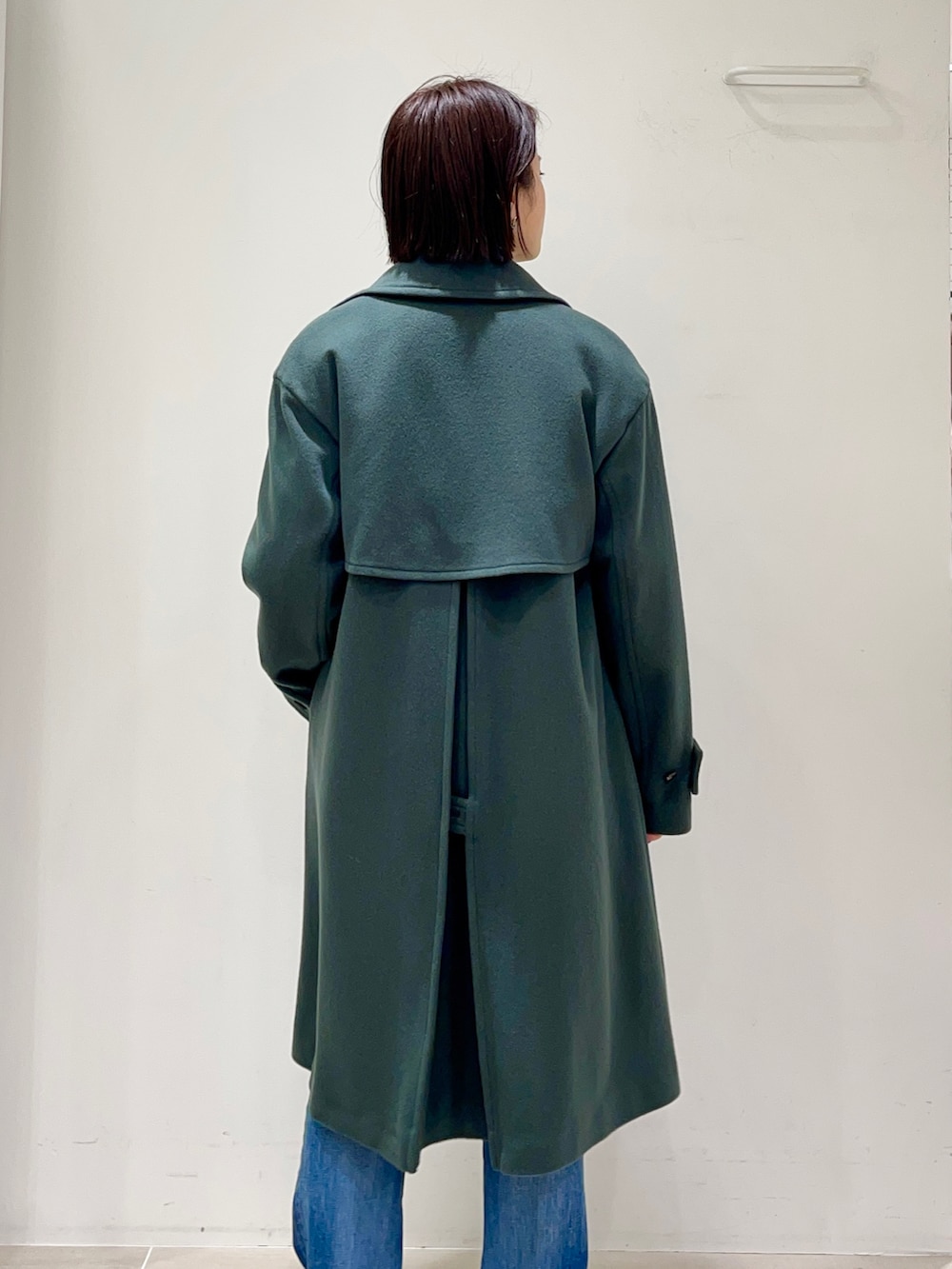 グリーン系のトレンチコート、ブラック系のワンピースを着用したレディースの冬コーディネートの5枚目の写真