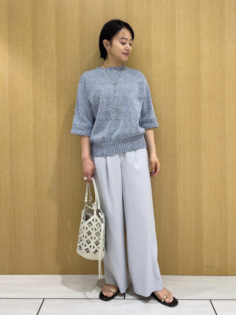 ブルー系のニット/セーター、ブルー系のその他パンツ、ホワイト系のハンドバッグを着用したレディースの春コーディネートの2枚目の写真