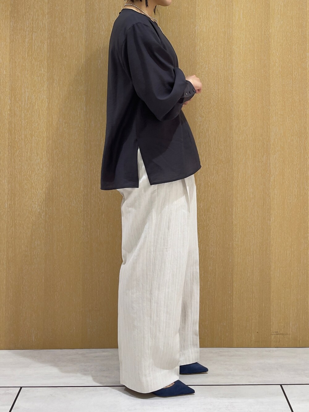 ベージュ系のスラックス、グレー系のシャツ/ブラウス、シルバー系のネックレスを着用したレディースの春コーディネートの5枚目の写真