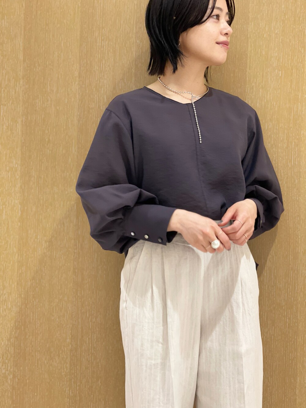 ベージュ系のスラックス、グレー系のシャツ/ブラウス、シルバー系のネックレスを着用したレディースの春コーディネートの4枚目の写真