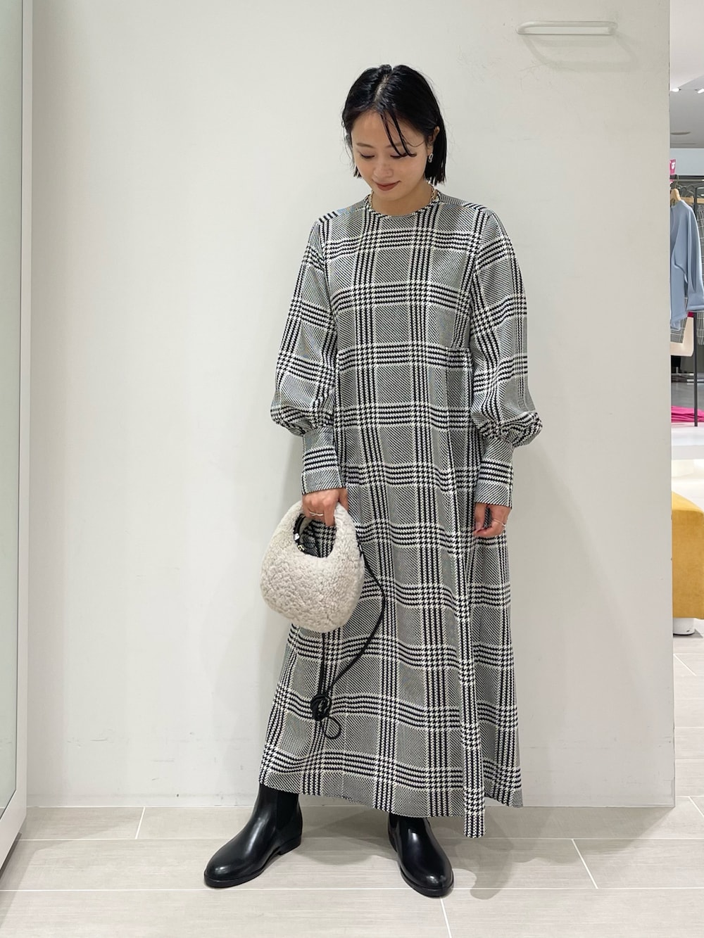 ホワイト系のショルダーバッグ、ホワイト系のカーディガン/ボレロ、ブラック系のブーツを着用したレディースの秋コーディネートの2枚目の写真