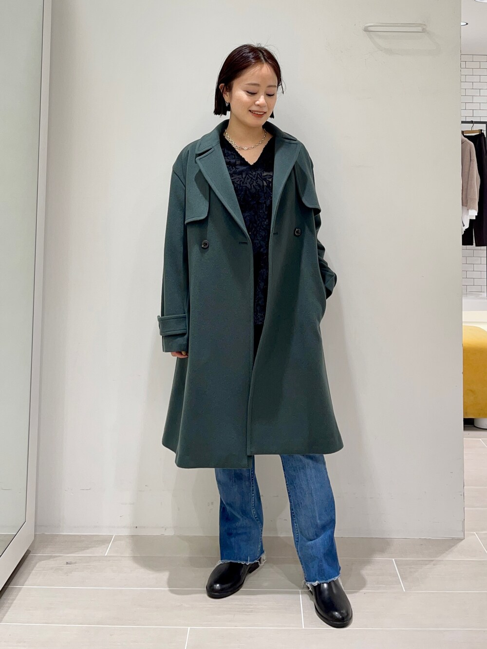 グリーン系のトレンチコート、ブラック系のワンピースを着用したレディースの冬コーディネートの3枚目の写真