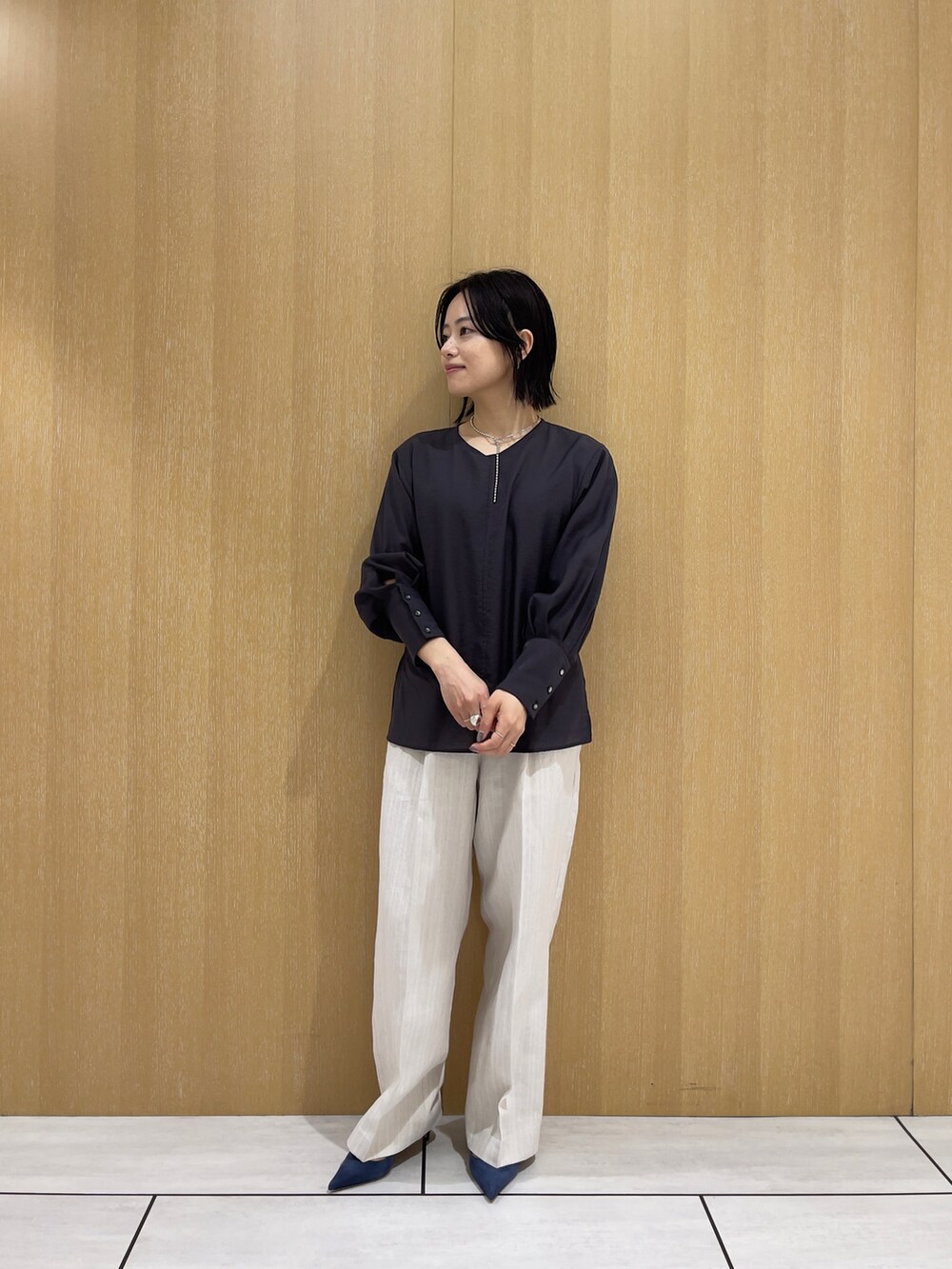 ベージュ系のスラックス、グレー系のシャツ/ブラウス、シルバー系のネックレスを着用したレディースの春コーディネートの3枚目の写真