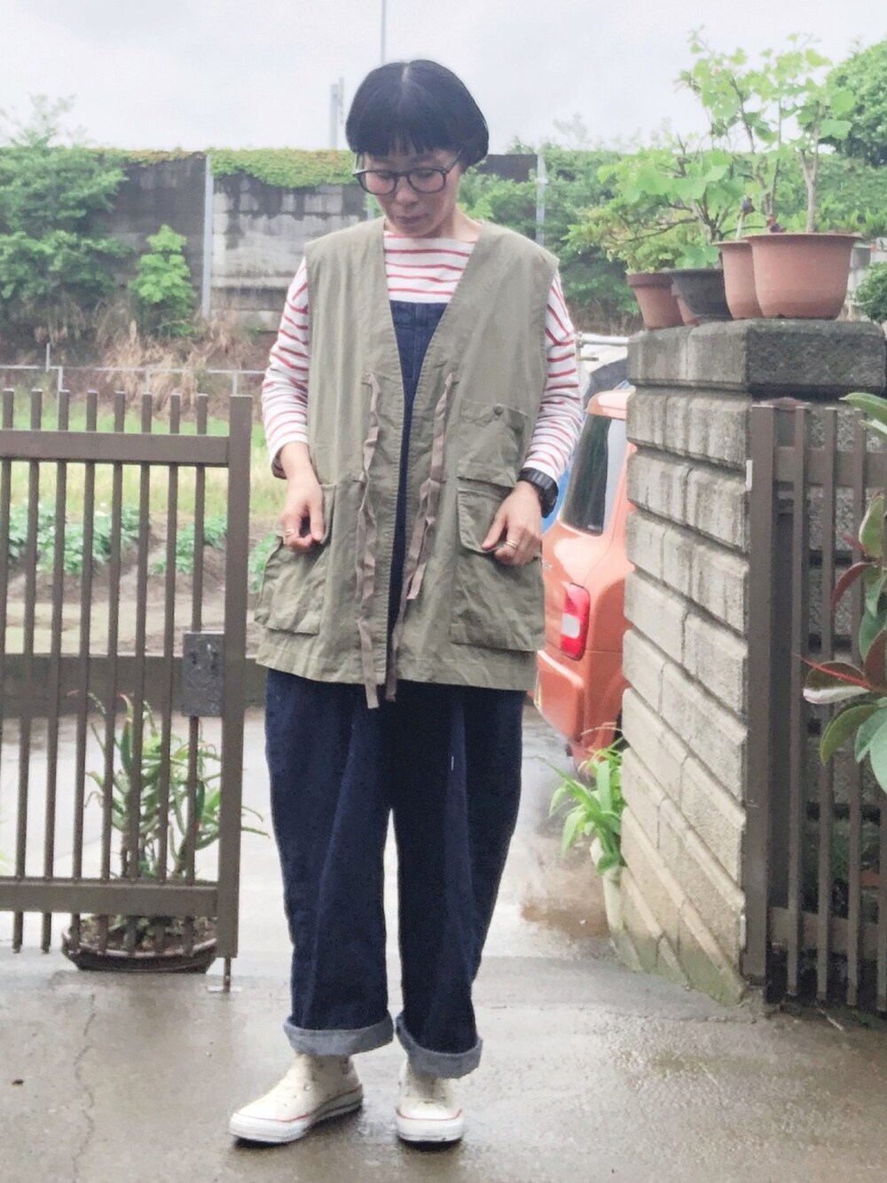 グリーン系のベスト、レッド系のTシャツ/カットソー、ブルー系のサロペット/オーバーオールを着用したレディースの春コーディネートの2枚目の写真