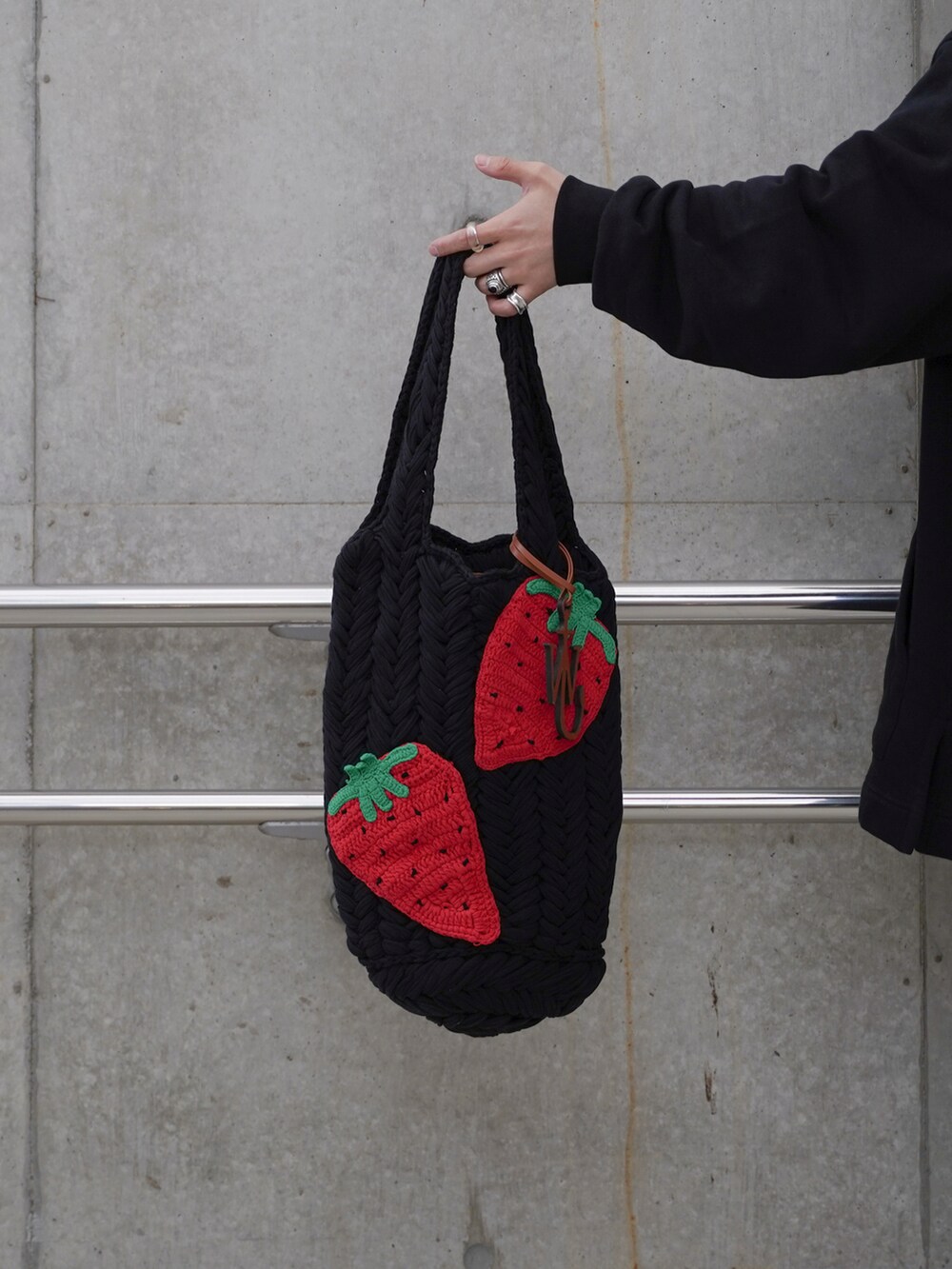 ブラック系のパーカー、ブラック系のハンドバッグ、ブラック系のパンツを着用したメンズの冬コーディネートの2枚目の写真