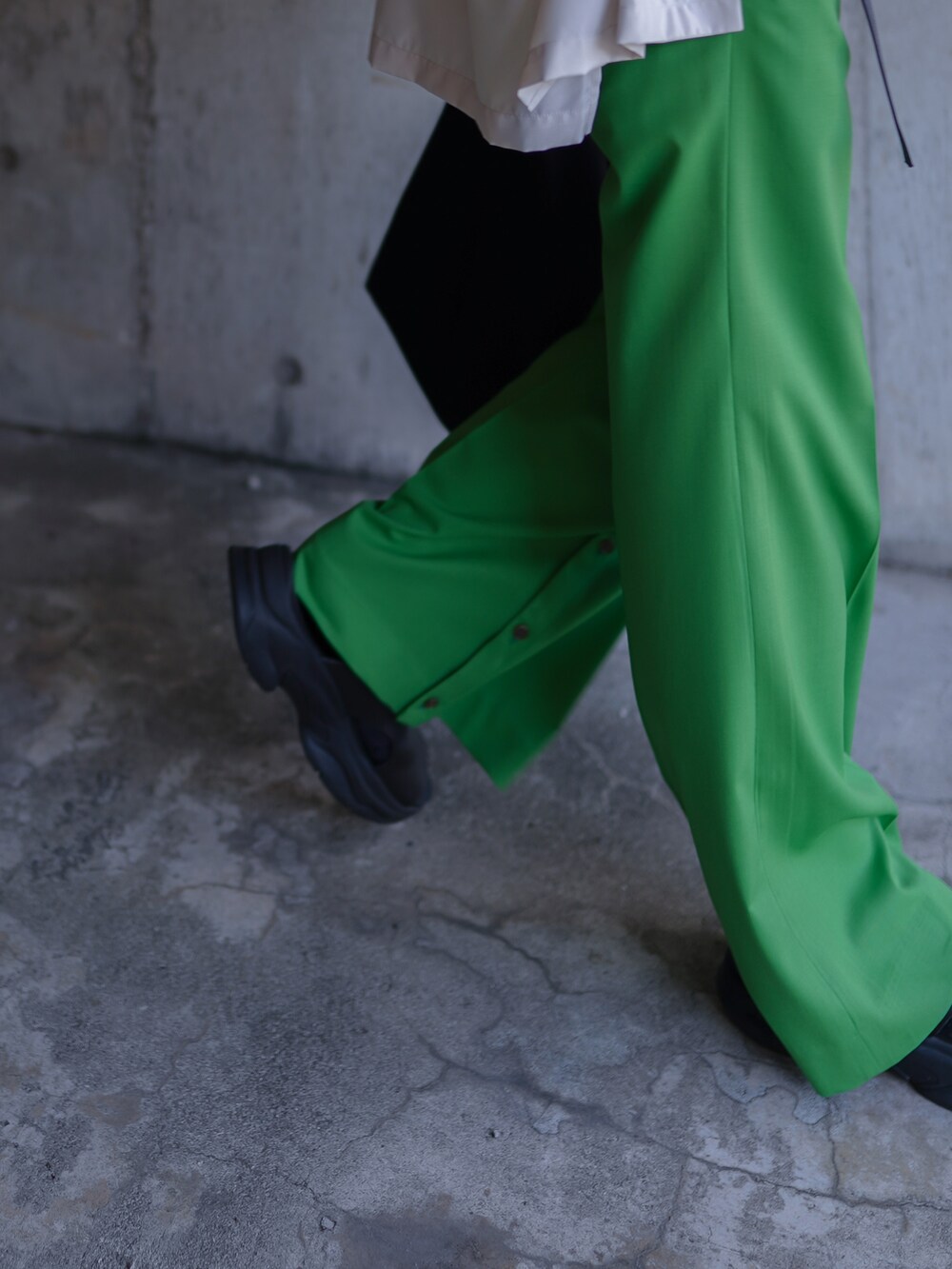 グリーン系のパンツ、ブラック系のバッグ、ホワイト系のTシャツ/カットソーを着用したメンズの夏コーディネートの4枚目の写真