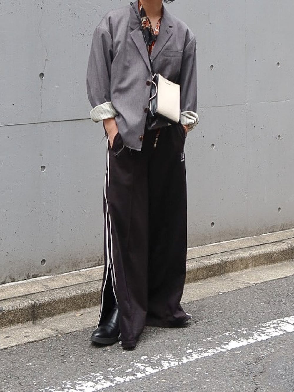 ブラック系のパンツ、グレー系のテーラードジャケット、ホワイト系のショルダーバッグを着用したメンズの秋コーディネートの2枚目の写真