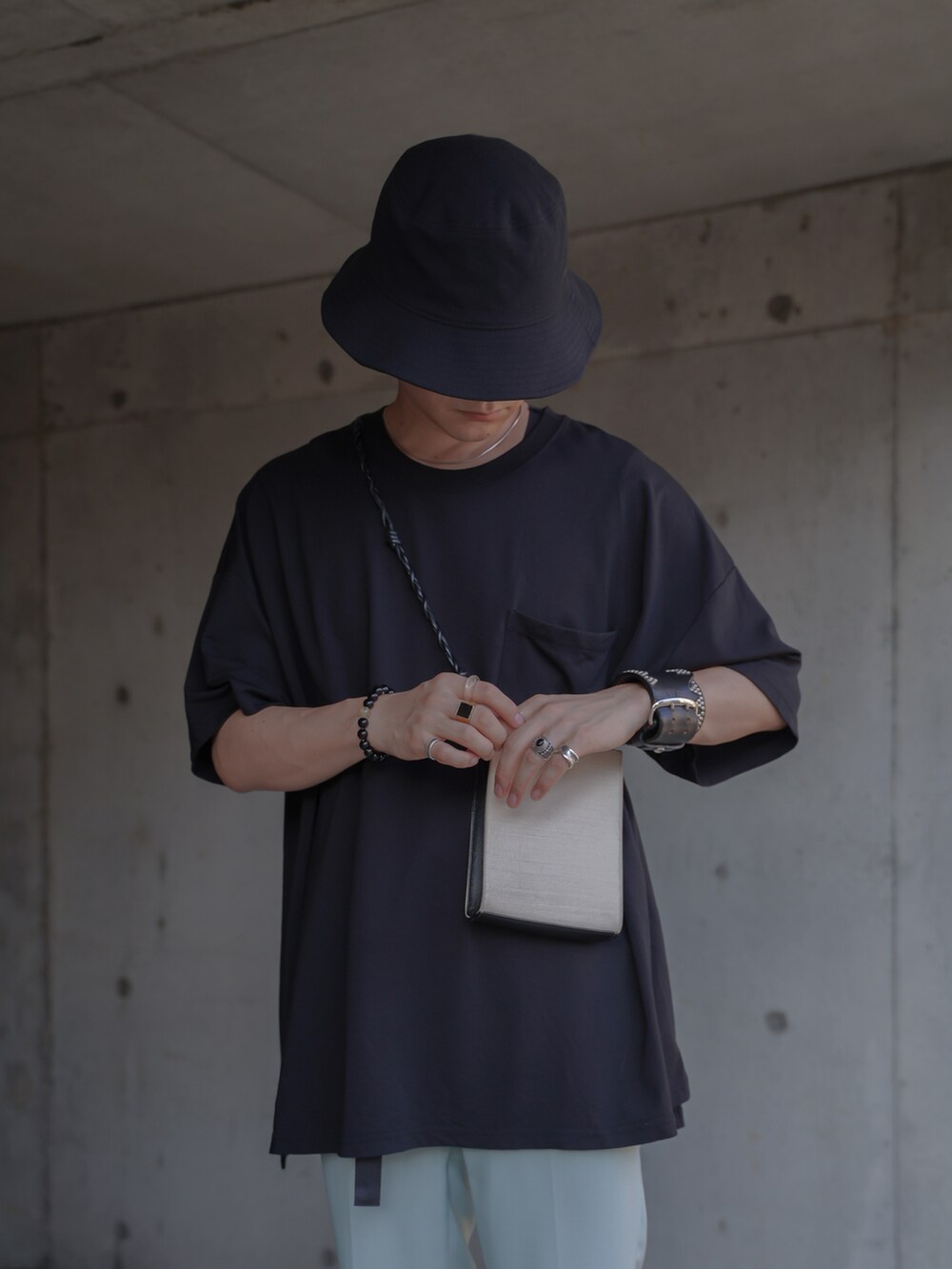 グリーン系のスラックス、ブラック系のサンダル、ホワイト系のショルダーバッグを着用したメンズの夏コーディネートの2枚目の写真