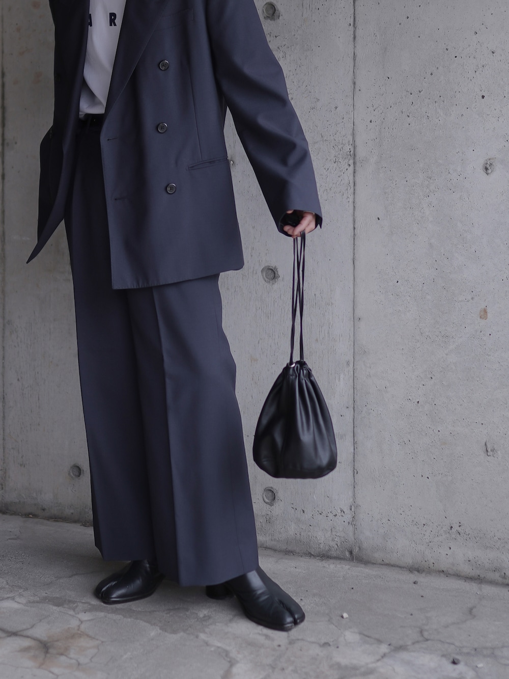 ホワイト系のTシャツ/カットソー、ブラック系のハンドバッグ、ブラック系のブーツを着用したメンズの春コーディネートの2枚目の写真