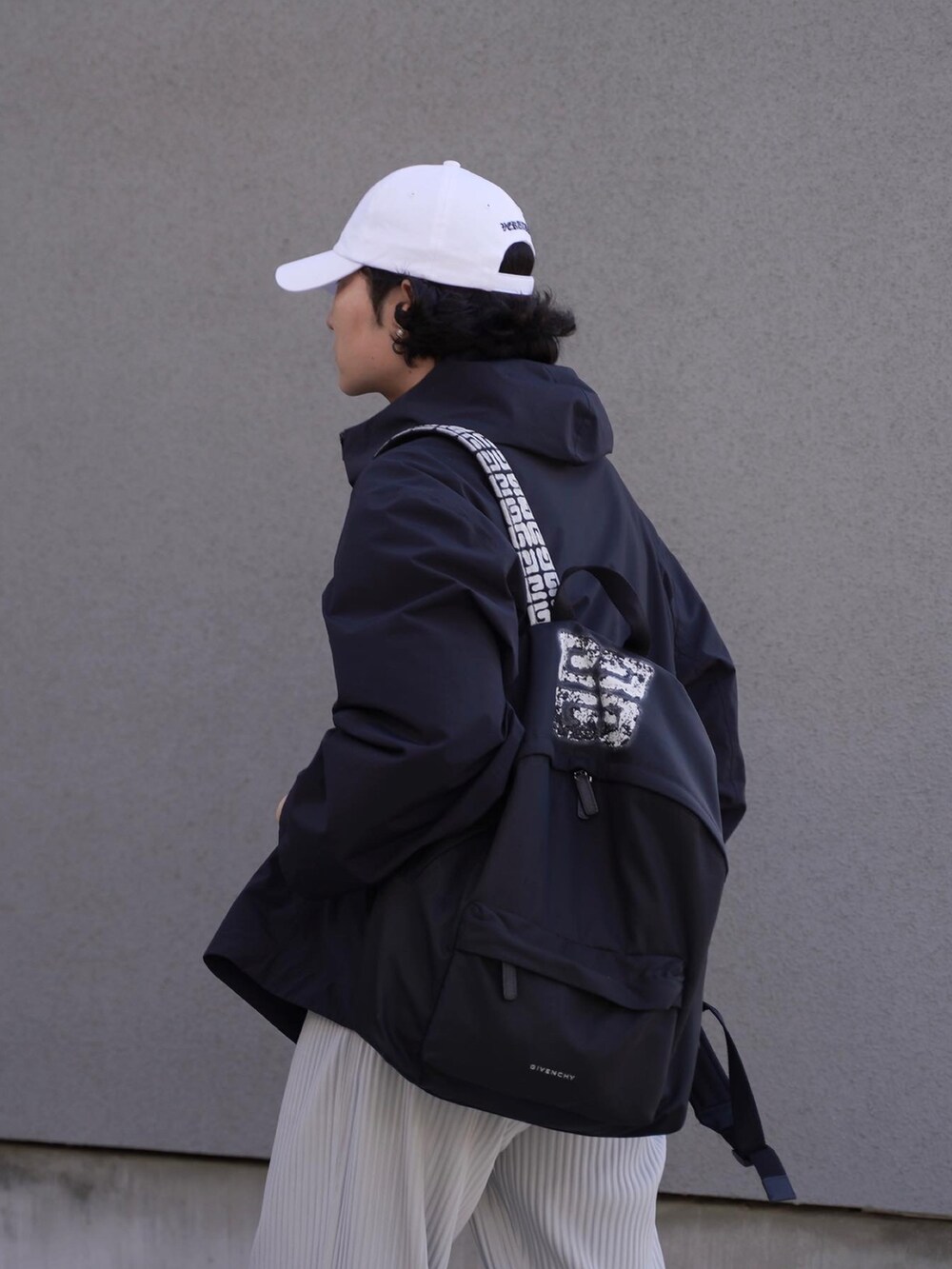 ブラック系のバックパック/リュック、ブラック系のマウンテンパーカー、グレー系のパンツを着用したメンズの春コーディネートの3枚目の写真